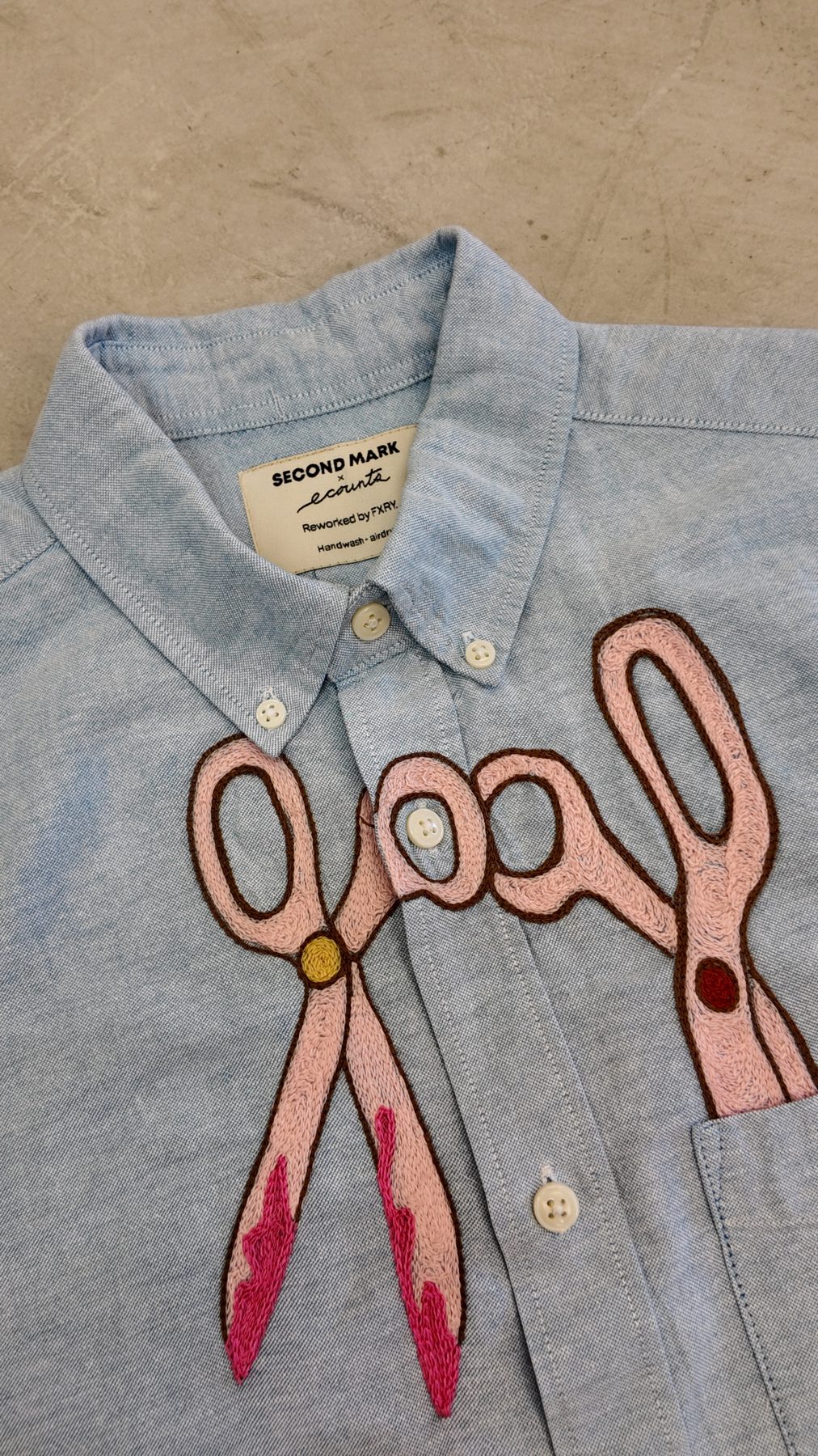 Pink scissors stitched across the chest