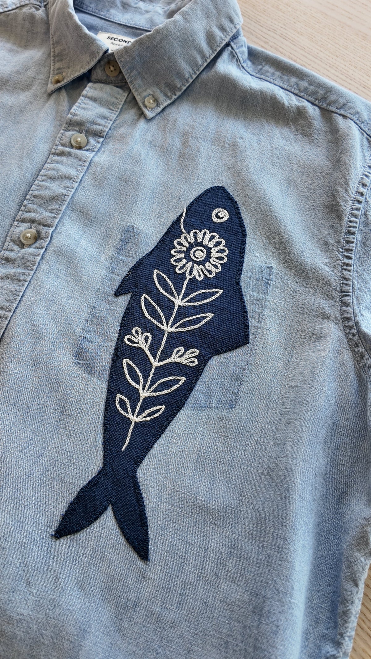 Front view of light blue button-down showing navy fish embroidery detail